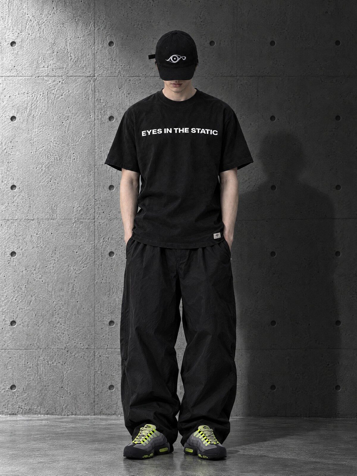 黒のロゴTシャツと黒のアイロゴキャップを着用したモデル